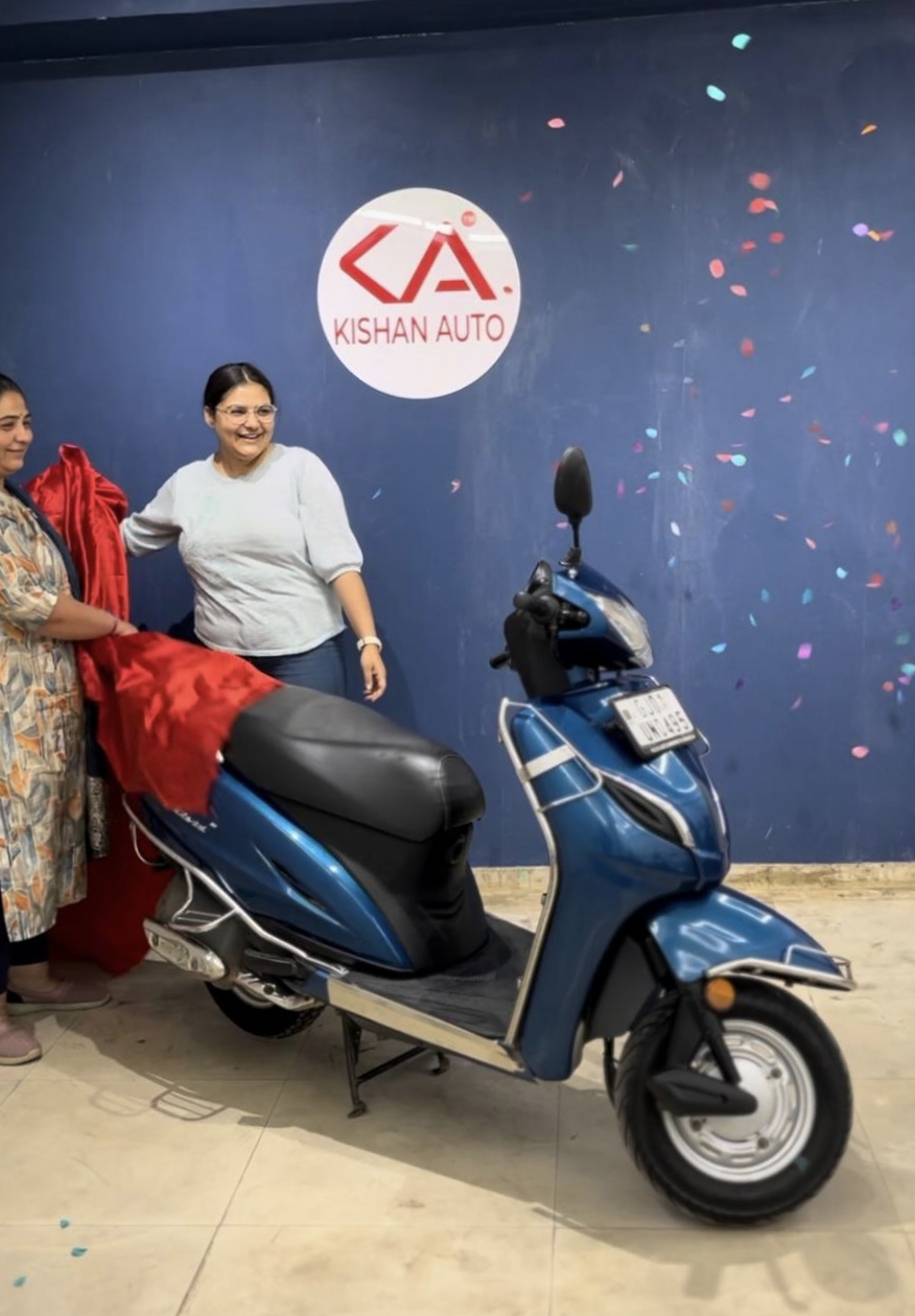 Family taking delivery of a used two-wheeler at Kishan Auto Consult showroom in Old Ahmedabad